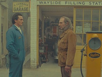 Movie still from “The Rat Catcher” (2023), directed by Wes Anderson – Two men standing in front of a building; Medium shot, Over the shoulder angle