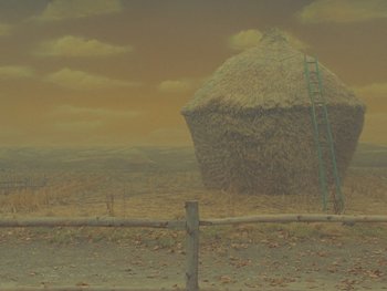 Movie still from “The Rat Catcher” (2023), directed by Wes Anderson – An image of an image of a hay stack in the middle of a field; Extreme Wide shot, Low angle