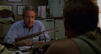 Movie still from “The Return of the Living Dead” (1985), directed by Dan O'Bannon – An older man sitting at a table talking to a woman; Medium shot, Over the shoulder angle