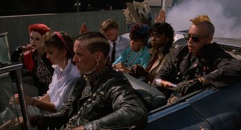 Movie still from “The Return of the Living Dead” (1985), directed by Dan O'Bannon – A group of people sitting in a car waving; Medium shot, High angle