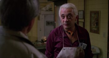 Movie still from “The Return of the Living Dead” (1985), directed by Dan O'Bannon – An older man wearing an apron talking to another man; Close Up shot, Over the shoulder angle