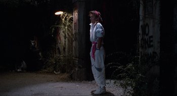 Movie still from “The Return of the Living Dead” (1985), directed by Dan O'Bannon – A person in a costume standing in the dark; Wide shot, Low angle