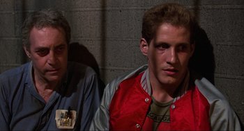 Movie still from “The Return of the Living Dead” (1985), directed by Dan O'Bannon – Two men sitting next to each other in front of a brick wall; Close Up shot, Over the shoulder angle