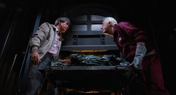 Movie still from “The Return of the Living Dead” (1985), directed by Dan O'Bannon – Two men are talking in front of an oven; Medium shot, Overhead angle