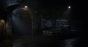 Movie still from “The Return of the Living Dead” (1985), directed by Dan O'Bannon – An old car parked under a street light at night; Extreme Wide shot, High angle