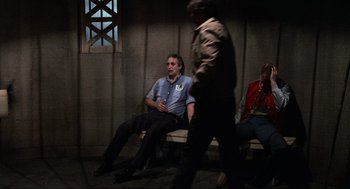 Movie still from “The Return of the Living Dead” (1985), directed by Dan O'Bannon – A group of men sitting on a bench in a room; Wide shot, Over the shoulder angle