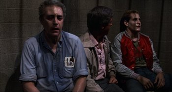 Movie still from “The Return of the Living Dead” (1985), directed by Dan O'Bannon – A group of men sitting next to each other on a bench; Medium shot, Over the shoulder angle