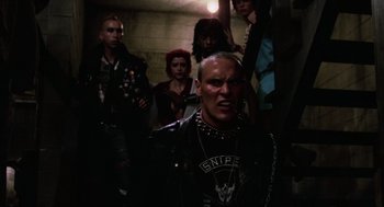 Movie still from “The Return of the Living Dead” (1985), directed by Dan O'Bannon – A group of people standing in a dark room; Medium shot, Low angle