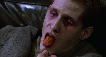 Movie still from “The Return of the Living Dead” (1985), directed by Dan O'Bannon – A man is eating a piece of food on a couch; Close Up shot, High angle