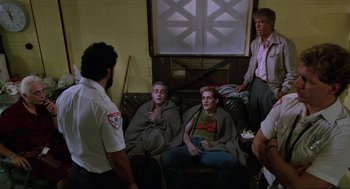 Movie still from “The Return of the Living Dead” (1985), directed by Dan O'Bannon – A group of people sitting on a couch in a room; Medium shot, Over the shoulder angle