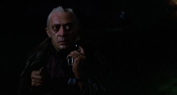Movie still from “The Return of the Living Dead” (1985), directed by Dan O'Bannon – An older man holding a cell phone in his hand; Close Up shot, Low angle
