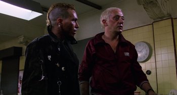 Movie still from “The Return of the Living Dead” (1985), directed by Dan O'Bannon – A man and a woman standing next to each other in a room; Medium shot, Over the shoulder angle