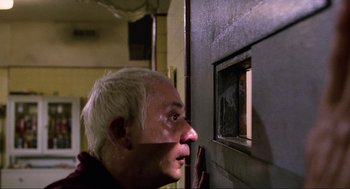 Movie still from “The Return of the Living Dead” (1985), directed by Dan O'Bannon – A man looking out a window in a room; Close Up shot, Low angle