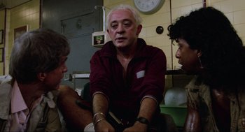 Movie still from “The Return of the Living Dead” (1985), directed by Dan O'Bannon – A group of people sitting in a room; Medium shot, Over the shoulder angle