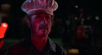 Movie still from “The Return of the Living Dead” (1985), directed by Dan O'Bannon – A man wearing a hat and a black shirt; Close Up shot, Low angle