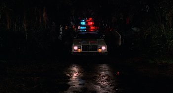 Movie still from “The Return of the Living Dead” (1985), directed by Dan O'Bannon – A police car is parked in the middle of the night; Extreme Wide shot, Low angle