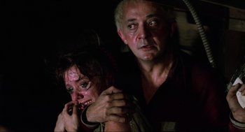 Movie still from “The Return of the Living Dead” (1985), directed by Dan O'Bannon – A man and a woman are crying in a dark room; Close Up shot, Over the shoulder angle