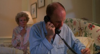 Movie still from “The Return of the Living Dead” (1985), directed by Dan O'Bannon – An older man talking on a phone while a woman looks on; Medium shot, Low angle