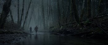 Movie still from “The Revenant” (2015), directed by Alejandro G. Iñárritu – A man is standing in the water in the woods; Extreme Wide shot, Low angle