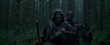 Movie still from “The Revenant” (2015), directed by Alejandro G. Iñárritu – Two men in the woods are walking through the woods; Medium shot, Low angle