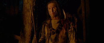 Movie still from “The Revenant” (2015), directed by Alejandro G. Iñárritu – A man in a native american costume with a knife; Medium shot, Low angle