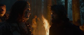 Movie still from “The Revenant” (2015), directed by Alejandro G. Iñárritu – Two people standing next to each other near a fire; Medium shot, Over the shoulder angle