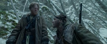 Movie still from “The Revenant” (2015), directed by Alejandro G. Iñárritu – Two men standing next to each other in the snow; Medium shot, Over the shoulder angle