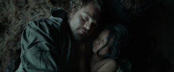 Movie still from “The Revenant” (2015), directed by Alejandro G. Iñárritu – A man and a child laying on the ground; Close Up shot, Overhead angle