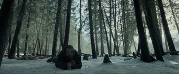 Movie still from “The Revenant” (2015), directed by Alejandro G. Iñárritu – A man laying on the ground in the woods; Wide shot, High angle
