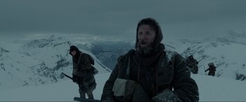 Movie still from “The Revenant” (2015), directed by Alejandro G. Iñárritu – A man and a woman in the snow on top of a mountain; Medium shot, Low angle