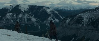 Movie still from “The Revenant” (2015), directed by Alejandro G. Iñárritu – A man with a backpack walking up a snowy hill; Extreme Wide shot, High angle