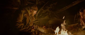 Movie still from “The Revenant” (2015), directed by Alejandro G. Iñárritu – A man is lighting a fire in the dark; Medium shot, Low angle