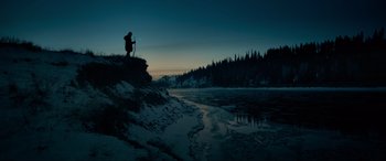 Movie still from “The Revenant” (2015), directed by Alejandro G. Iñárritu – A man standing on a hill overlooking a frozen river; Extreme Wide shot, Low angle