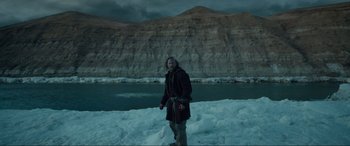 Movie still from “The Revenant” (2015), directed by Alejandro G. Iñárritu – A man standing on top of a snow covered slope; Wide shot, Low angle