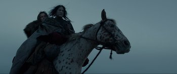 Movie still from “The Revenant” (2015), directed by Alejandro G. Iñárritu – A person riding a horse in a field; Medium shot, Low angle