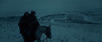 Movie still from “The Revenant” (2015), directed by Alejandro G. Iñárritu – A person riding a horse on a snowy field; Wide shot, High angle