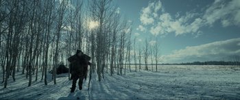 Movie still from “The Revenant” (2015), directed by Alejandro G. Iñárritu – A man is running through the snow near a forest; Extreme Wide shot, Low angle