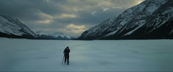 Movie still from “The Revenant” (2015), directed by Alejandro G. Iñárritu – A man standing in the snow with a snowboard; Extreme Wide shot, High angle