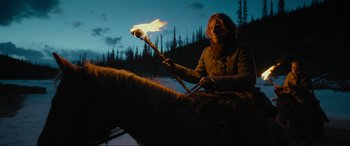 Movie still from “The Revenant” (2015), directed by Alejandro G. Iñárritu – A person holding a stick with a fire in it; Wide shot, Low angle