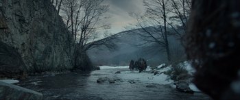 Movie still from “The Revenant” (2015), directed by Alejandro G. Iñárritu – A group of people riding horses across a river; Extreme Wide shot, Low angle