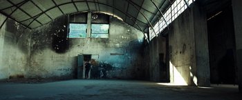 Movie still from “The Ritual Killer” (2023), directed by George Gallo – Two people standing in an empty room with an open door; Extreme Wide shot, High angle