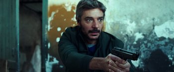 Movie still from “The Ritual Killer” (2023), directed by George Gallo – A person holding a gun; Close Up shot, Low angle