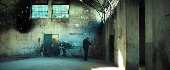 Movie still from “The Ritual Killer” (2023), directed by George Gallo – A man standing in an empty room holding a cell phone; Wide shot, Low angle