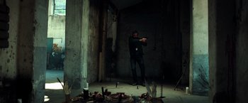 Movie still from “The Ritual Killer” (2023), directed by George Gallo – A man standing in a dark room holding a gun in his hand; Wide shot, High angle