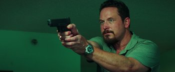Movie still from “The Ritual Killer” (2023), directed by George Gallo – A man holding a gun in a room; Close Up shot, Low angle