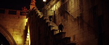 Movie still from “The Ritual Killer” (2023), directed by George Gallo – A man walking up a set of stairs at night; Extreme Wide shot, Low angle