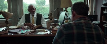 Movie still from “The Ritual Killer” (2023), directed by George Gallo – Two men sitting at a table in front of a laptop; Medium shot, Over the shoulder angle