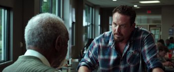 Movie still from “The Ritual Killer” (2023), directed by George Gallo – A man in a plaid shirt talking to another man; Close Up shot, Over the shoulder angle