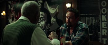 Movie still from “The Ritual Killer” (2023), directed by George Gallo – Two men are sitting at a table drinking beer; Medium shot, Over the shoulder angle