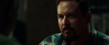 Movie still from “The Ritual Killer” (2023), directed by George Gallo – A person wearing a plaid shirt; Close Up shot, Over the shoulder angle